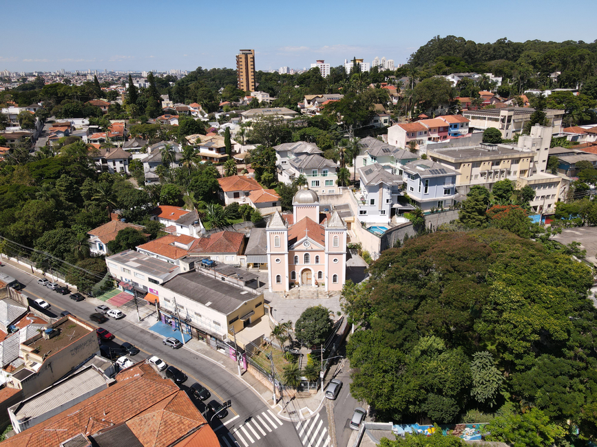 Paisagem urbana aérea mostrando uma igreja cercada por uma área residencial exuberante em São Paulo.